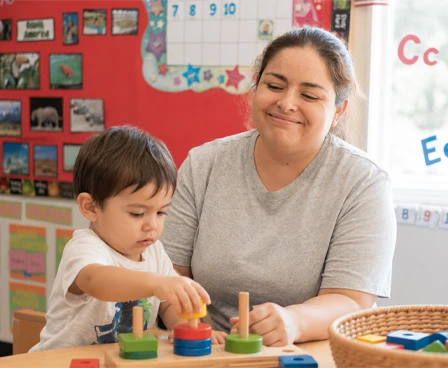 A caregiver and toddler playing with a stacking toy